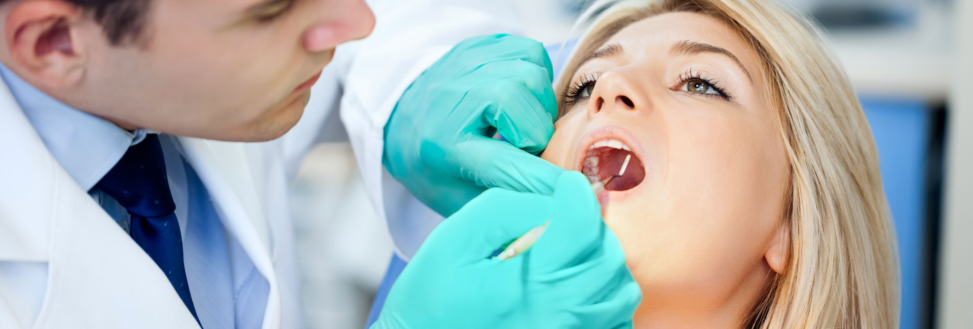 Dentist examining female patients teeth